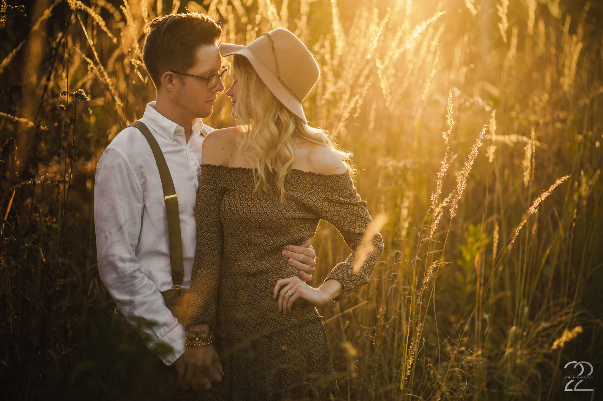 Man and woman snuggle close to one another in a field during sunset at Wegerzyn Garden Metropark by Dayton Wedding Photographer Studio 22 Photography